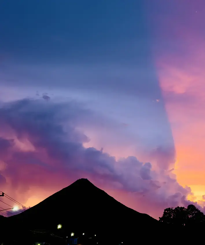 Silueta del Volcán Arenal bajo un cielo púrpura al anochecer