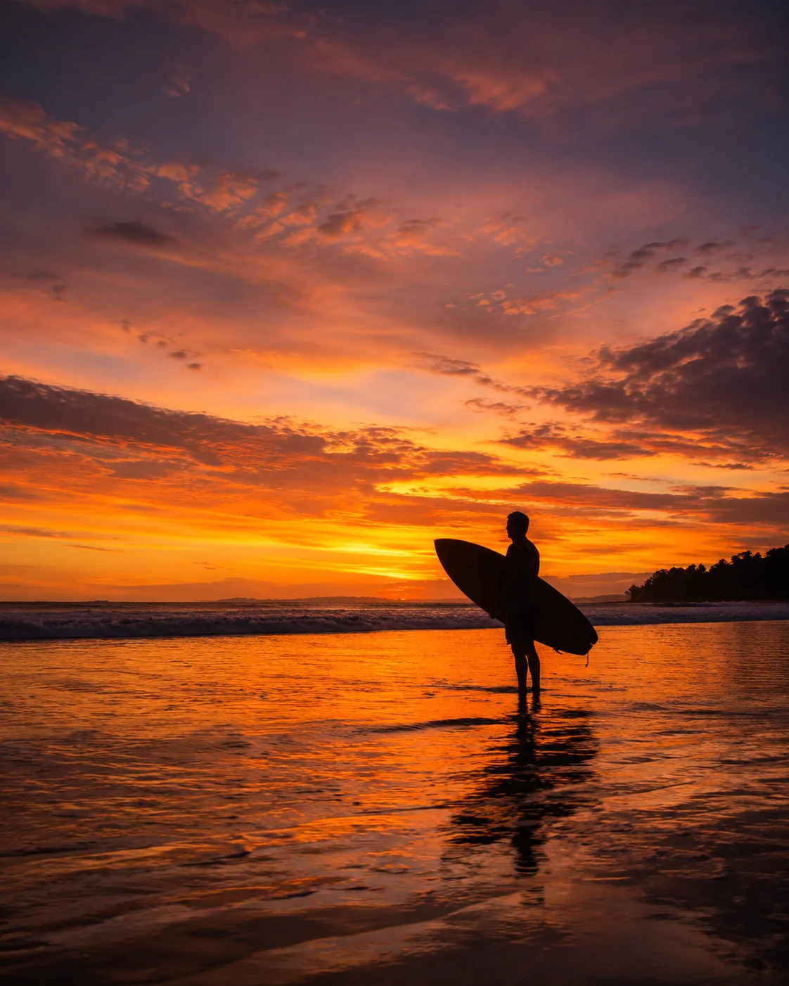 Surfer walking the shore at sunset in Costa Ballena