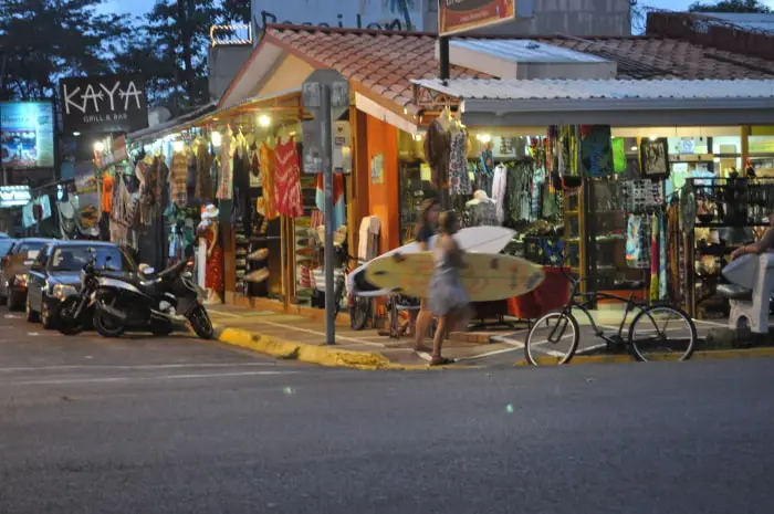 Surfer crossing the street by the surf shops of downtown Jacó
