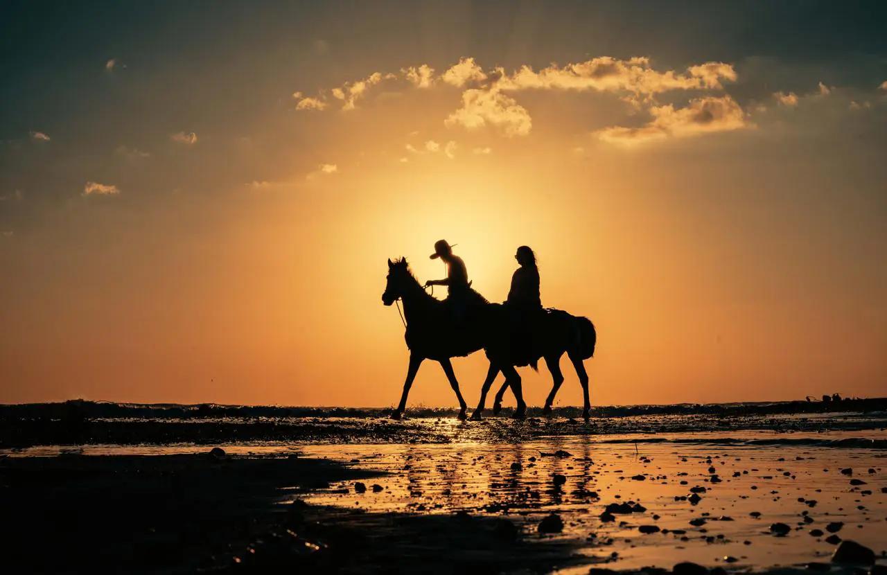 Two riders crossing the shore at low tide in Jacó