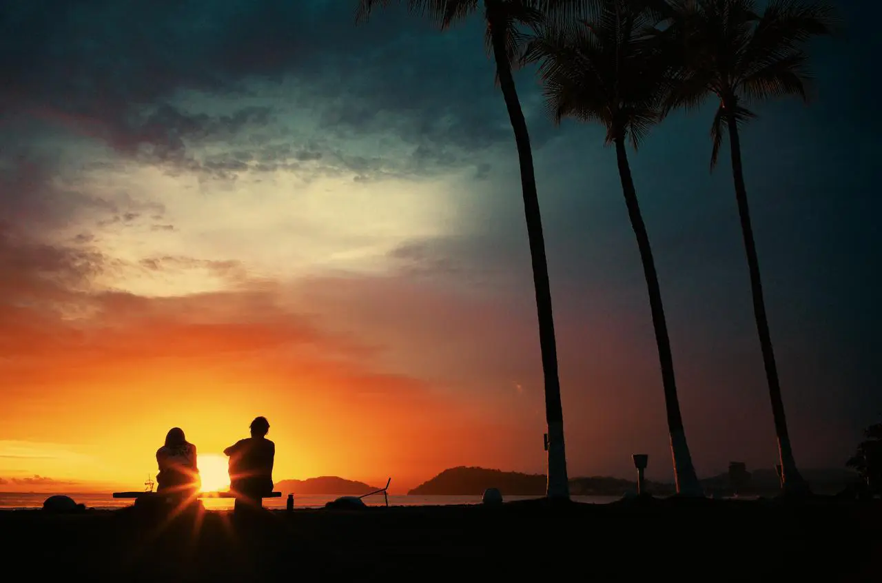 Couple watching the sunset under the palms in Jacó