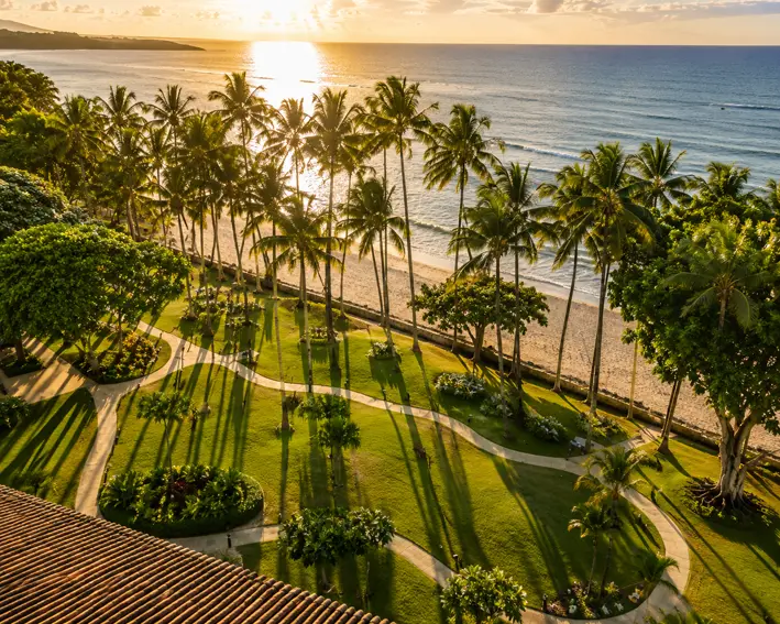 Jardines frente al mar y palmeras a la hora dorada en Tamarindo